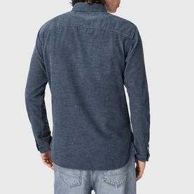 Model wearing All Saints moonstone blue long sleeve shirt, back view, styled with light wash jeans.