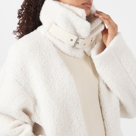 Model wearing Max Mara Sportmax ecru teddy fleece coat, close-up of silver buckle collar detail, styled over cream roll-neck top