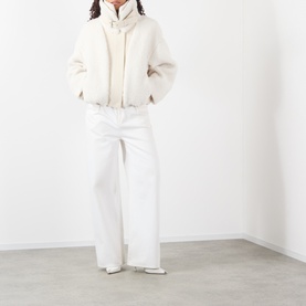 Model wearing Max Mara Sportmax ecru cropped zip-up coat with wide-leg white trousers and white heeled boots.