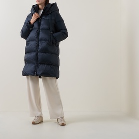 Model wearing Max Mara Cube midnight blue hooded quilted down coat, styled with cream wide-leg trousers and beige shoes.