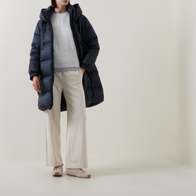 Model wearing Max Mara Cube Midnight Blue hooded quilted down coat, styled with grey knit, cream wide-leg trousers and white trainers.