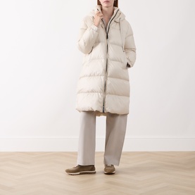 Model wearing Max Mara Cube vanilla quilted hooded down coat, styled with grey wide-leg trousers and tan flat shoes.