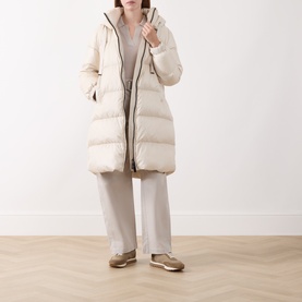 Model wearing Max Mara Cube vanilla quilted down coat with hood, styled with wide-leg trousers and metallic trainers.