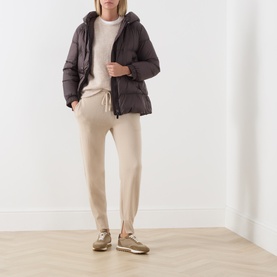 Model wearing Max Mara Cube dark brown quilted hooded puffer jacket, styled with beige joggers and tan trainers.