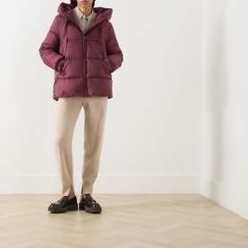 Model wearing burgundy hooded puffer jacket with zip fastening, styled with beige trousers and black loafers