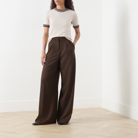 Model wearing Max Mara S Carina Contrast Trim Sweater in Albino with wide-leg brown trousers. Short sleeves, contrast stripe trim detail.