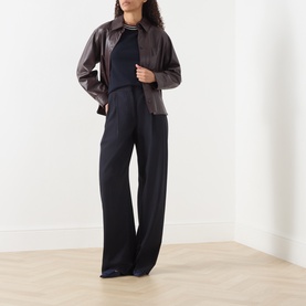 Model wearing Max Mara S Carina Contrast Trim Sweater in Ultramarine, styled with dark brown leather jacket and wide-leg black trousers.