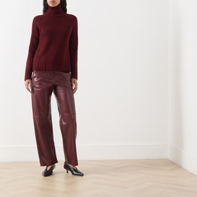 Model wearing Max Mara S Mantova Turtleneck Sweater in bordeaux with chunky ribbed trims, styled with matching bordeaux leather trousers and black