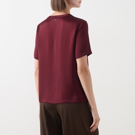 Model wearing Max Mara S Rebecca Solid T-Shirt in bordeaux, crew neck, short sleeves, smooth finish, styled with brown wide-leg trousers.