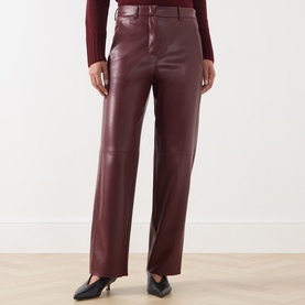 Model wearing Max Mara S Sospiro Faux Leather Straight Trousers in bordeaux, styled with a dark red top and black shoes.