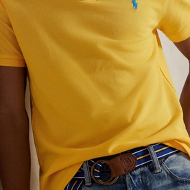 Model wearing Ralph Lauren Yellow Fin Regular Polo with blue embroidered pony logo, styled with denim jeans and striped belt.
