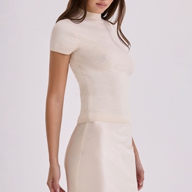 Model wearing House of CB ivory short-sleeve mock-neck fitted top, styled with matching ivory midi skirt