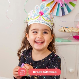 Child wearing a decorated multicolour paper crown, smiling, holding a Tiger Tribe colouring pencil, with party decorations in the background