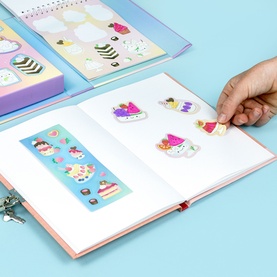 Tiger Tribe multi sticker book open showing colourful cake and sweet-themed stickers, with hand peeling a sticker from the page