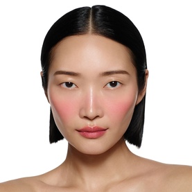 Model wearing Victoria Beckham Beauty Blusher in Fiore, a soft pink-rose shade applied to cheeks for a flushed, natural finish.