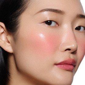 Model with Victoria Beckham Beauty Blusher in Fiore, shown as a soft rosy flush applied to cheekbones and lips