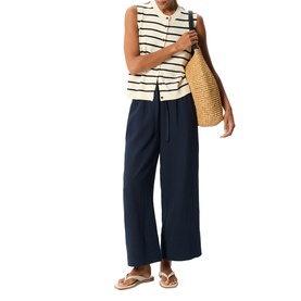 Model wearing Whistles blue wide-leg trousers with white navy striped sleeveless top, styled with tan woven tote bag and nude sandals.