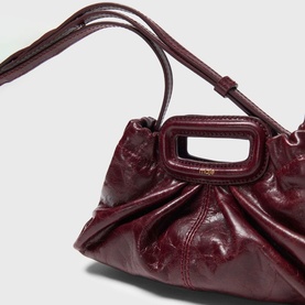 Burgundy patent leather shoulder bag with gold-tone M handle, adjustable strap, and ruched body detail