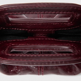 Deep burgundy patent leather wallet open, revealing card slots, clear ID window, and zip compartment interior