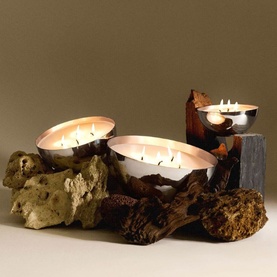 Alessi Candle Container with Lid in 18/10 stainless steel, styled with lit multi-wick candles on driftwood in a lifestyle arrangement.