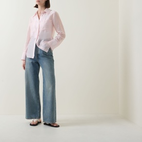 Model wearing Aligne light pink linen blend shirt with wide-leg blue jeans and floral flat sandals.