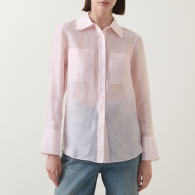 Model wearing Aligne light pink semi-sheer linen blend shirt with chest pocket and wide cuffs, styled with blue jeans.