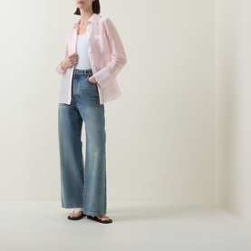 Model wearing Aligne light pink linen blend shirt, styled with white tee, wide-leg blue jeans and brown flat sandals.