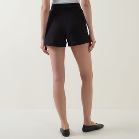 Model wearing Aligne black linen-blend mini skirt, styled with black ballet flats, rear view showing tailored silhouette