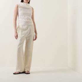 Model wearing Aligne Dana Sheer Textured Blouse in ivory with draped neckline, styled with wide-leg cream trousers and dark sandals.