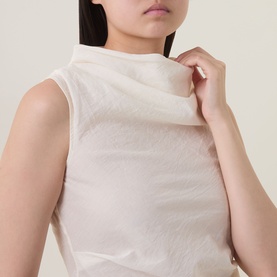 Model wearing Aligne Dana Sheer Textured Blouse in ivory, featuring draped cowl neckline and sleeveless semi-sheer textured design