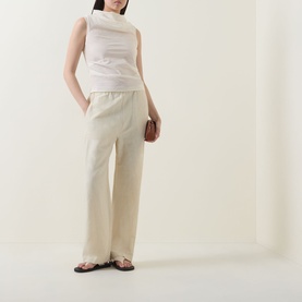 Model wearing Aligne Dana Sheer Textured Blouse in ivory with cowl neckline, styled with wide-leg cream trousers and black sandals