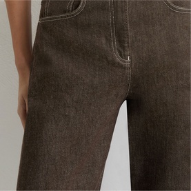 Model wearing Reiss brown denim wide-leg trousers with contrast white stitching, close-up of hip and leg detail