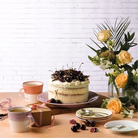 Royal Doulton multi-coloured tableware set styled with a cherry cream cake, fresh flowers, and scattered cherries on a wooden table