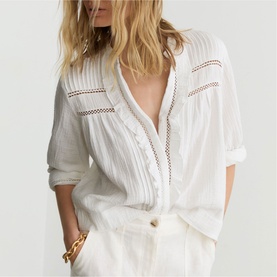 Model wearing Reiss white button-front blouse with lace trim inserts and V-neckline, styled with white wide-leg trousers and gold chain bracelet