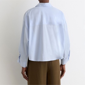 Model wearing Reiss blue long-sleeve cropped shirt, back view, styled with olive trousers