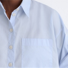 Model wearing Reiss blue shirt dress, close-up showing button placket and chest patch pocket in lightweight fabric