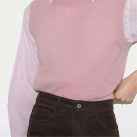 Model wearing Jigsaw pink knitted vest over a light pink long-sleeve shirt, styled with dark brown corduroy trousers.