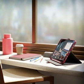 Cygnett red tablet folio case propped open on a desk, styled with a notebook, pens, and coffee cup by a sunlit window.