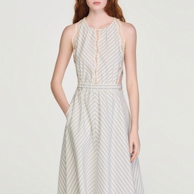Model wearing Sandro Womens French Dress in ecru and blue diagonal stripe, sleeveless midi length with button front detail and cinched waist