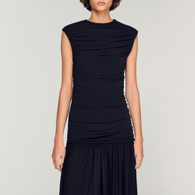 Model wearing Sandro Womens French Dress in black, featuring ruched detailing, cap sleeves, and a pleated drop-waist skirt.