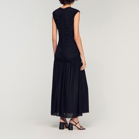 Model wearing Sandro Womens French Dress in black, ruched bodice, tiered maxi skirt, styled with black strappy heeled sandals, back view.