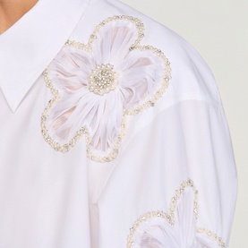 Model wearing Sandro white and blue shirt with oversized floral appliqu&eacute; embellished with pearls and gold beading