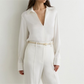 Model wearing Reiss white V-neck long-sleeve blouse, styled with matching white wide-leg trousers and a white belt with gold hardware.