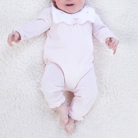 Emile Et Rose pale pink baby all-in-one with scalloped collar and floral embroidery detail, worn by baby model lying on white fur