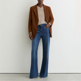 Model wearing Reiss mid blue flared jeans with front seam detail, styled with a camel blazer and cream knit top