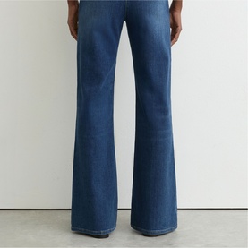 Model wearing Reiss mid blue flared jeans, rear view showing wide-leg silhouette and full length cut