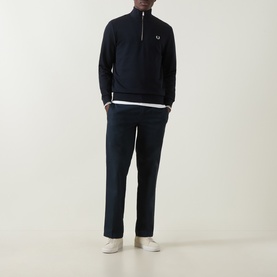 Model wearing Fred Perry Laurel Wreath Logo Half-Zip Sweatshirt in navy, styled with navy trousers and white trainers.