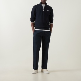 Model wearing Fred Perry Laurel Wreath Logo Half-Zip Sweatshirt in navy, styled with navy trousers and white trainers.