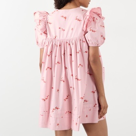 Model wearing Ganni Angel Floral Print Mini Dress in Silver Pink with frill shoulders, short sleeves, and floral print, shown from behind.