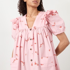 Model wearing Ganni Angel Floral Print Mini Dress in Silver Pink with frill shoulders, V-neckline, short sleeves and front button fastening